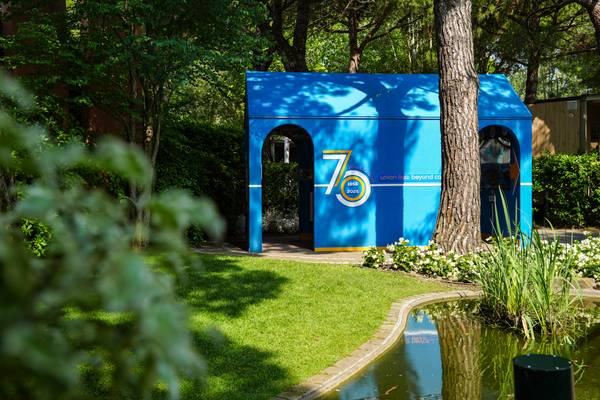 Edificio azul con cartel de '75 años' en un parque.