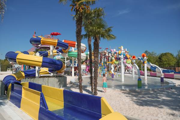 Parque acuático en el camping Union Lido Mare con toboganes coloridos y niños jugando.