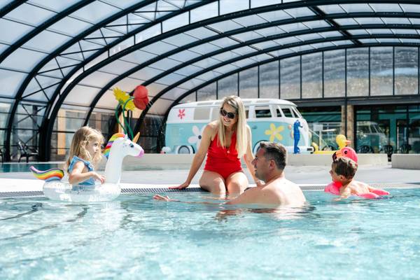 Familie nyder af en svømning i et overdækket pool med en enhjørning-floater.