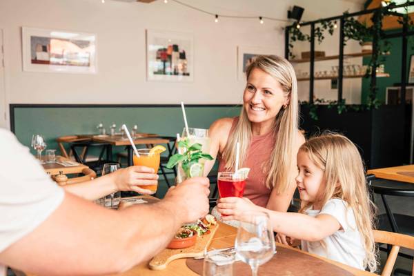 Familie sidder i restaurant på Camping Village L`Océan Breton og nyder drikkevarer og mad.
