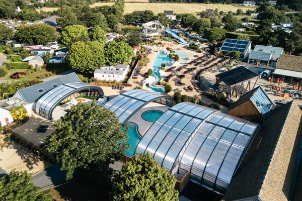 Aerial view of Camping Village L'Océan Breton with pools, slides, and buildings.