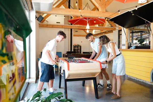 Trois personnes jouant au baby-foot au Camping Village L`Océan Breton.