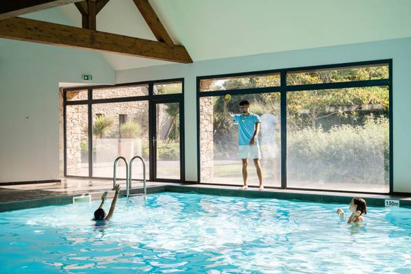Instructeur avec ballon près d'une piscine avec deux enfants