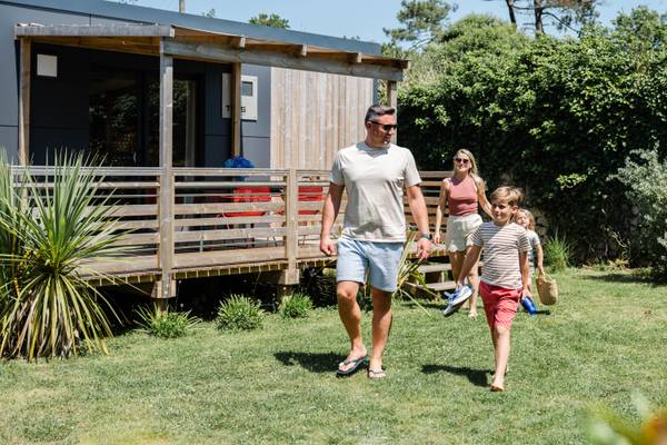 Une famille marchant dans le jardin devant une maison au Camping Village L`Ocean Breton