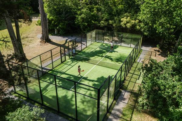 Vue aérienne des courts de tennis dans une forêt entourés d'arbres au Camping Village L`Océan Breton.