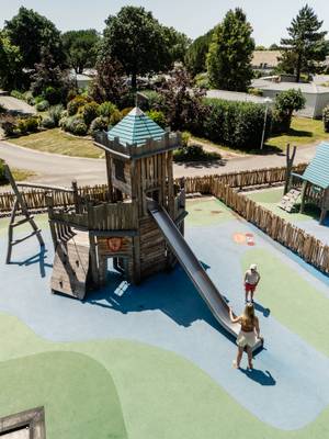 Aire de jeux au Camping Village L`Océan Breton avec une tour de château et une glissade.