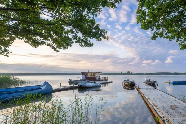 Campingplatz mit mehreren weißen Wohnwagen am See unter blauem Himmel.