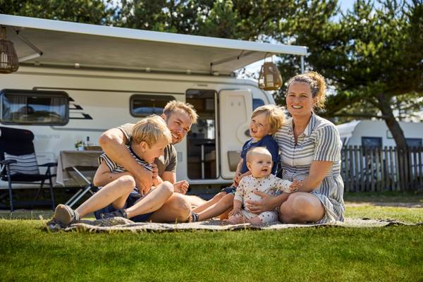 A family with two kids sitting on a blanket near their camper van at Henne Strand Resort