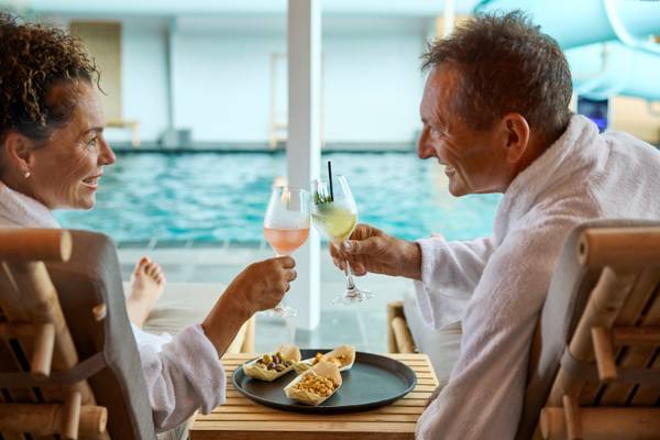 Couple celebrating at Henne Strand Resort with drinks and snacks on a table.