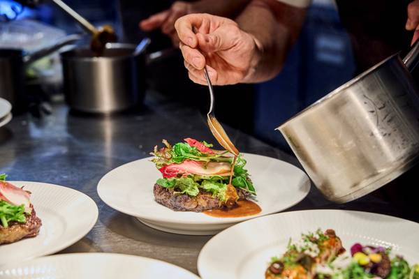 Chef at Henne Strand Resort garnishing a steak dish with sauce