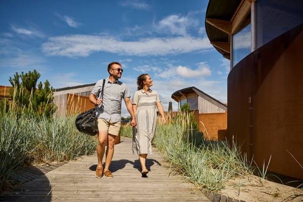 Couple walking on path at Henne Strand Resort with modern architecture in background