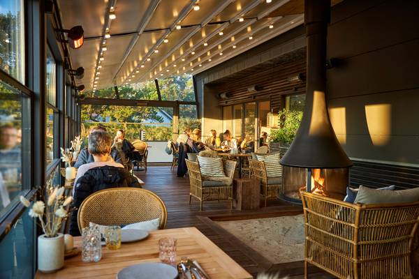 Guests sitting on chairs in the terrace of Henne Strand Resort Campsite with a fireplace