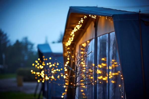 A cozy nighttime view of a tent with lit branches and fairy lights at Henne Strand Resort.
