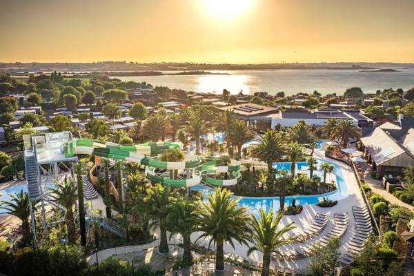 Vista aérea del Camping Les Mouettes con un tobogán acuático y piscina al atardecer.