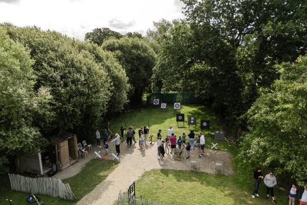 Grupo de personas practicando tiro con arco en el Camping Les Mouettes con objetivos y equipo en un área boscosa.