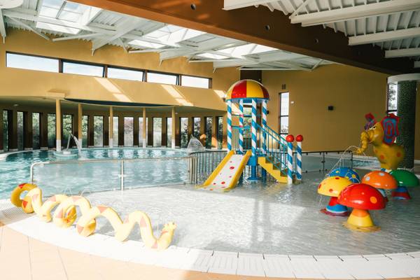 Área de piscina cubierta en Camping Les Mouettes con un tobogán y fuentes de agua en forma de hongo.