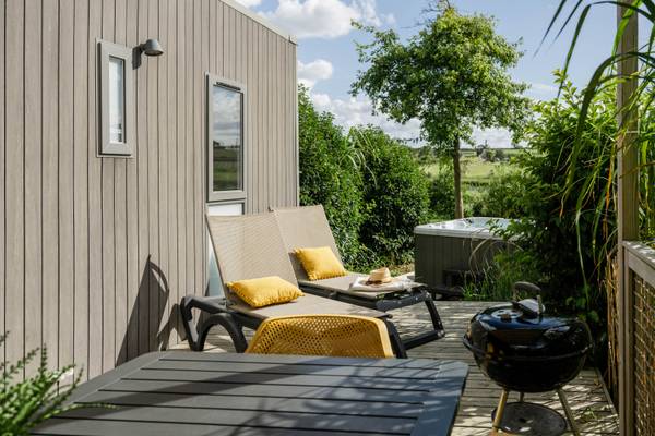 Área de lounge exterior en Camping Les Mouettes con dos tumbonas, una mesa y un jacuzzi.