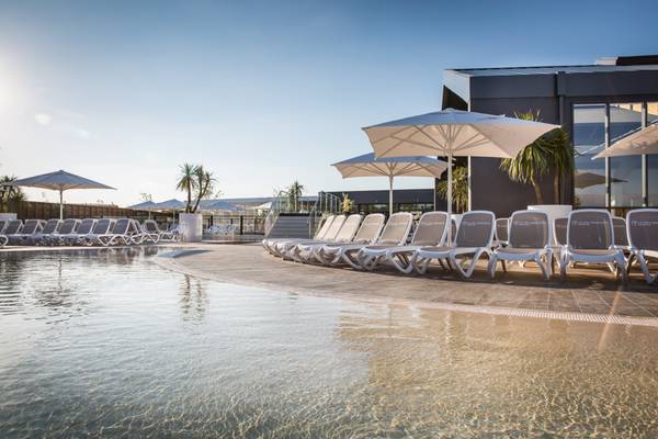Espace piscine extérieure avec chaises longues et parasols au Camping Le Pin Parasol.