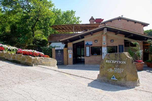 Edificio de recepción del camping Barco Reale con un gran letrero de piedra que dice recepción