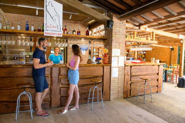Un hombre y una mujer se paran en una barra de bar de madera en el camping Barco Reale.