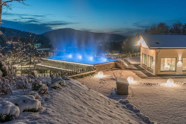 Una piscina al aire libre en Camping Resort Bodenmais, rodeada de nieve y montañas