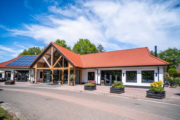 Luchtfoto van Papillon Country Resort camping met groene velden, bomen en een vijver bij zonsondergang.