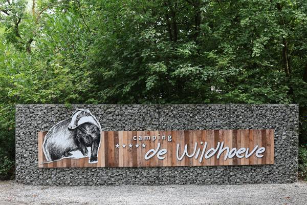 Indgangsskilt for Camping De Wildhoeve med en badger og træplanker