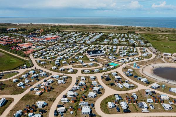 Vue aérienne d'un camping près de la mer avec de nombreuses tentes et voitures.