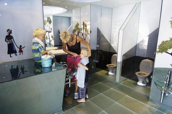 Una mujer mayor ayuda a dos niños a cepillarse los dientes en el baño del Jambo Feriepark.