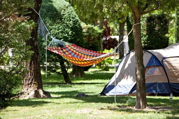 Una hamaca colorida y una tienda de campaña se encuentran en el camping Nature Parc L`Ardéchois.