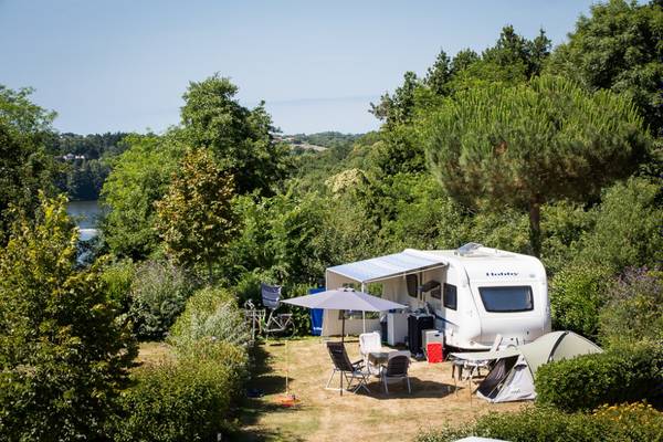 Camping Le Pin Parasol avec un camping-car sous les arbres près du lac