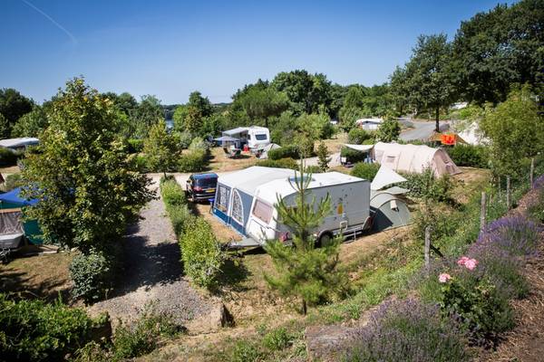 Camping avec des camping-cars et des tentes sous les arbres
