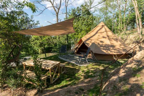 Ein Campingzelt mit Tisch und Stühlen in einem bewaldeten Gebiet.