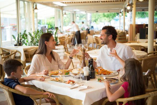 En familie spiser på et restaurant med et bord og retter.