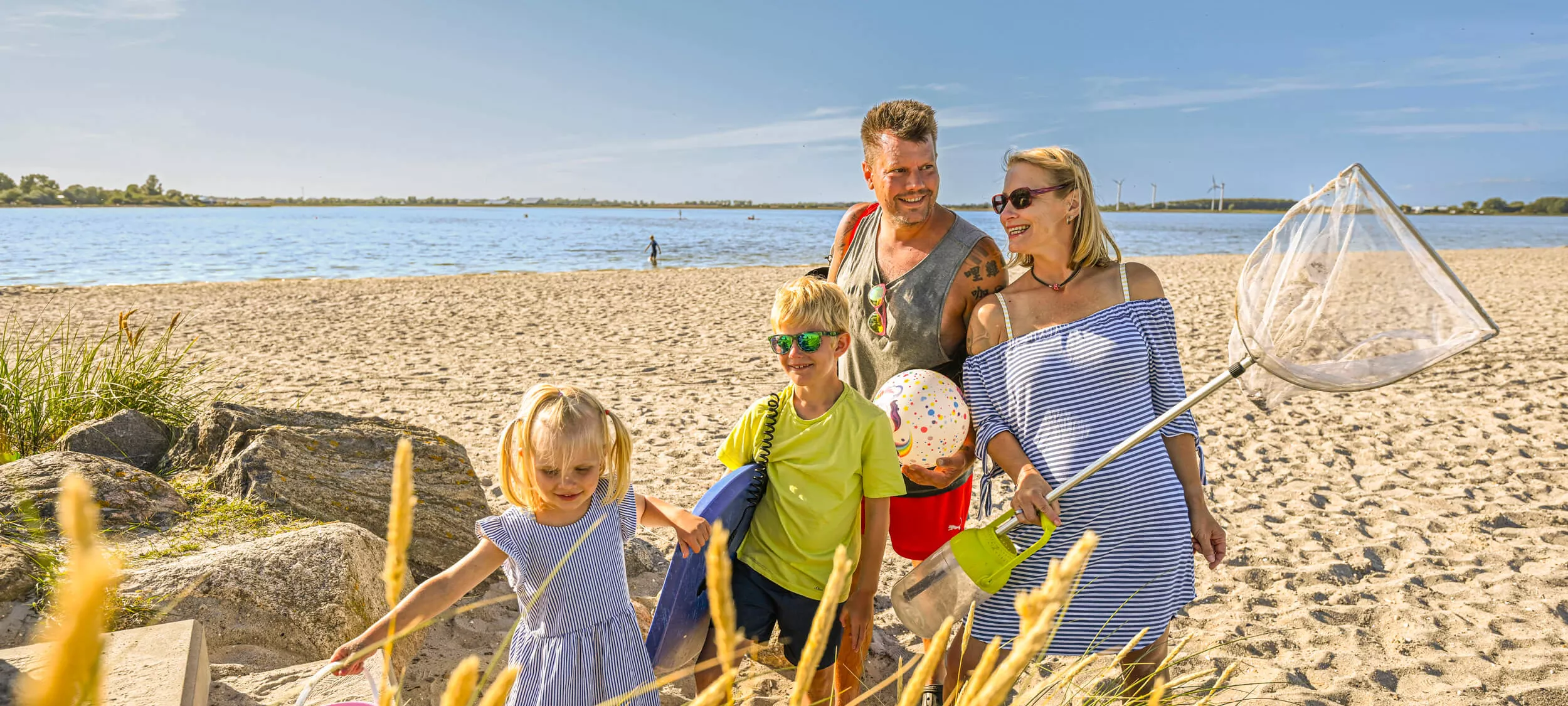 En familie med børn står på stranden ved Wulfener Hals.