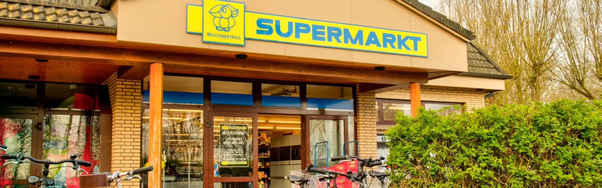 Forside af Wulfener Hals supermarked med gul skilt og parkerede cykler udenfor