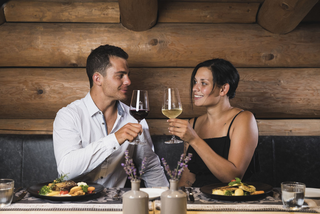 Coppia in un ristorante in legno con bevande e cibo sul tavolo.