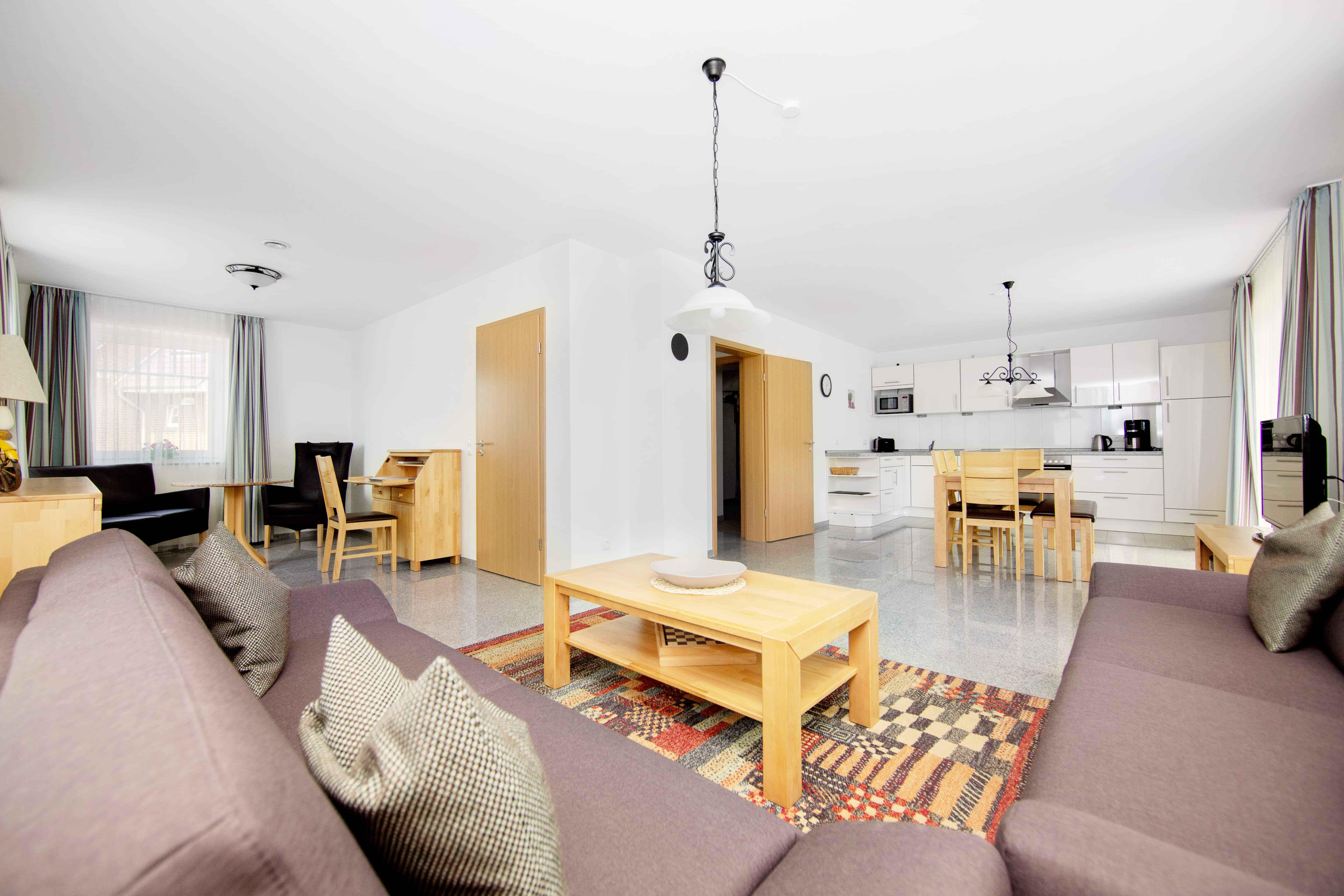 Interiør i stuen på Ostseecamping Heide med sofaer, kaffebord og spiseplads.