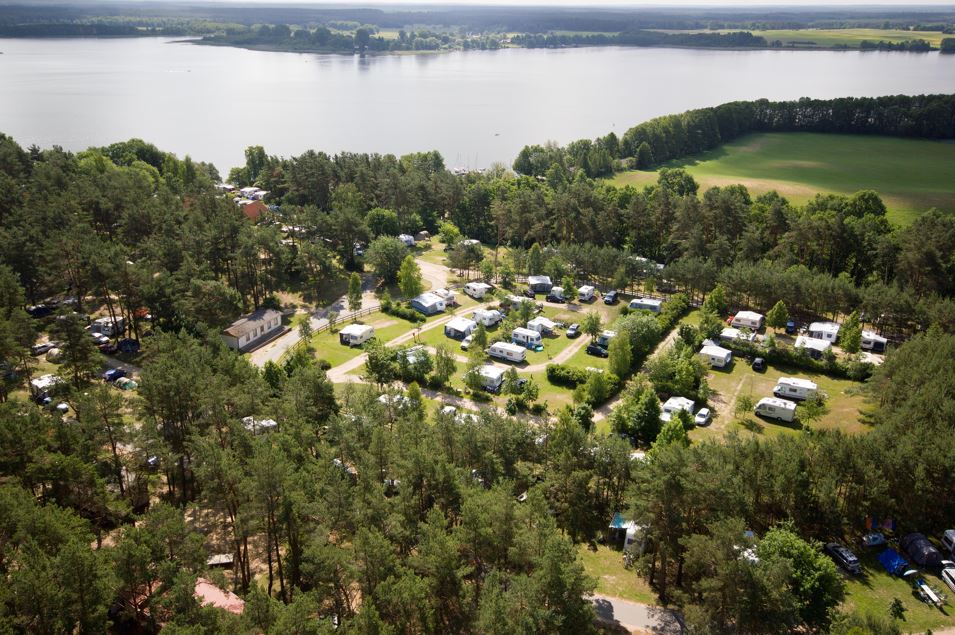 Aerial view of Camping- und Ferienpark Havelberge with many campsites by a lake.