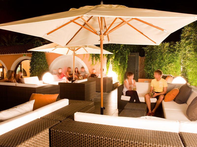 Area lounge serale al Playa Montroig Camping Resort con persone sedute sotto gli ombrelloni.