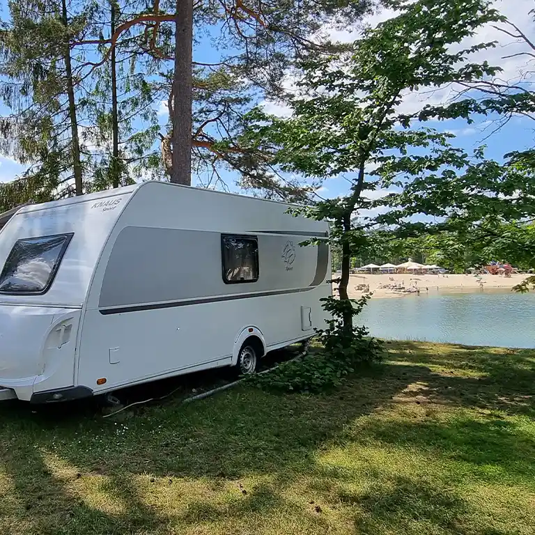 Weißer Wohnwagen am Südsee-Camp in einem Waldgebiet neben einem See