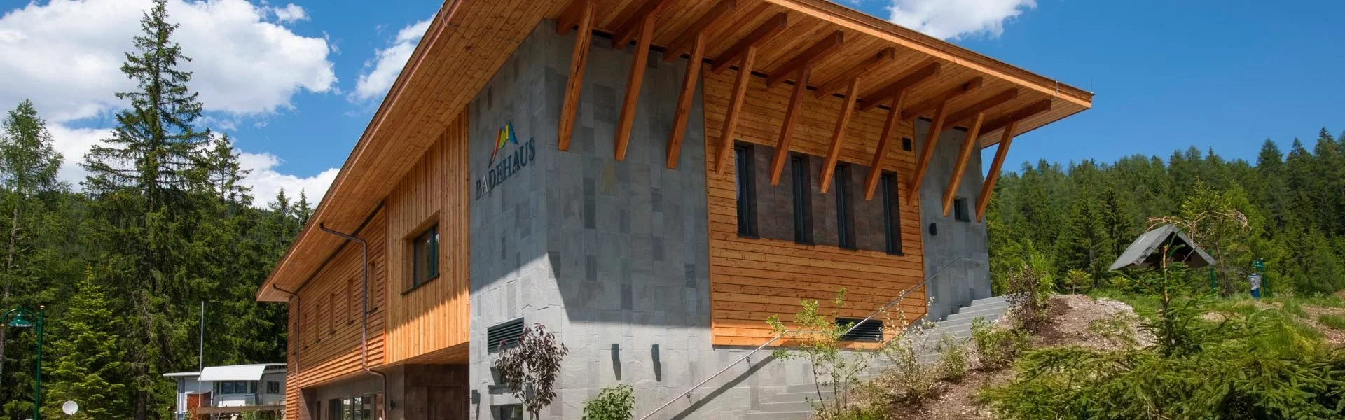 Zugspitz Resort campsite building with wooden exterior and stone walls, surrounded by trees.