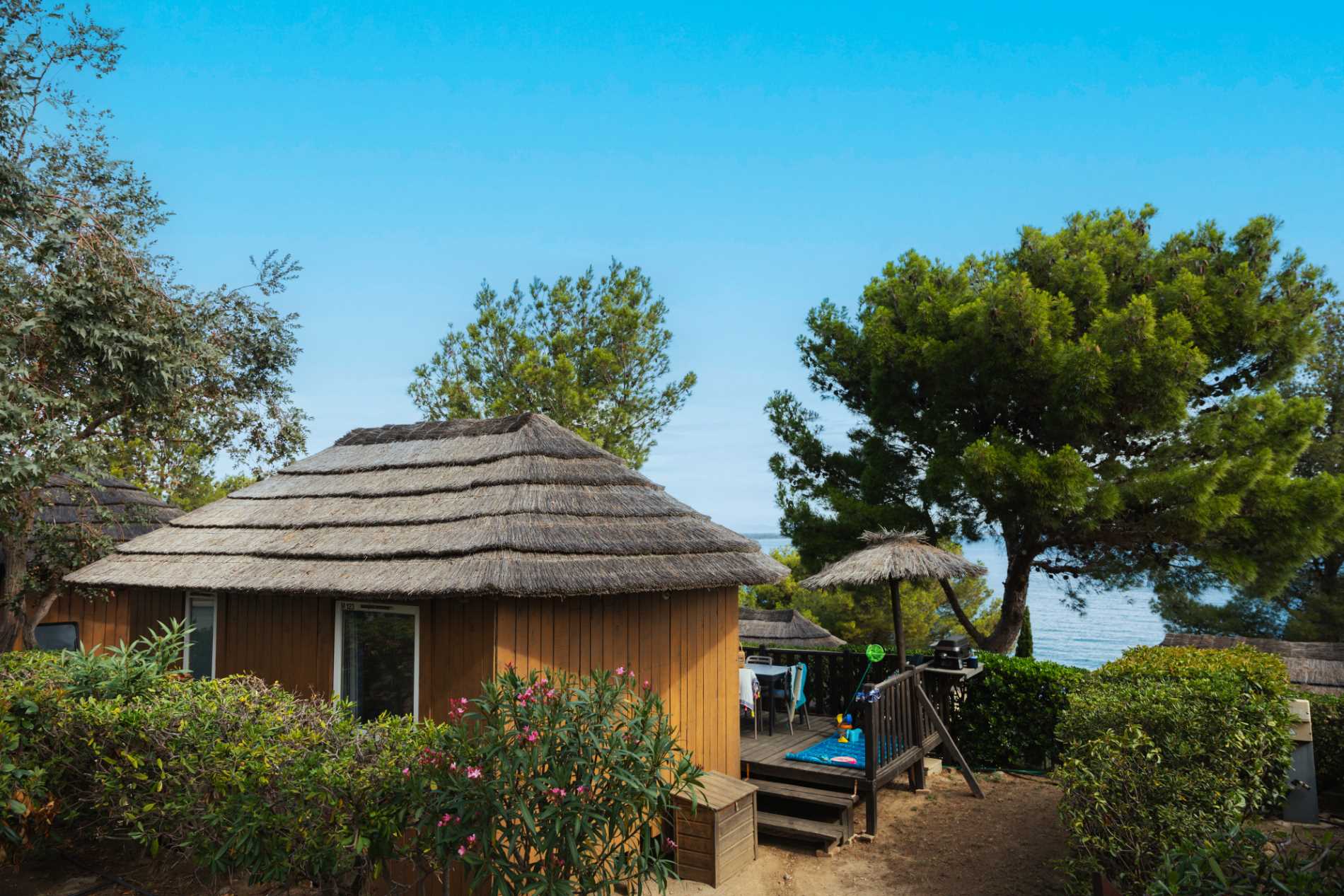 A small thatched hut at Camping Les Criques de Porteils with a view of the sea.