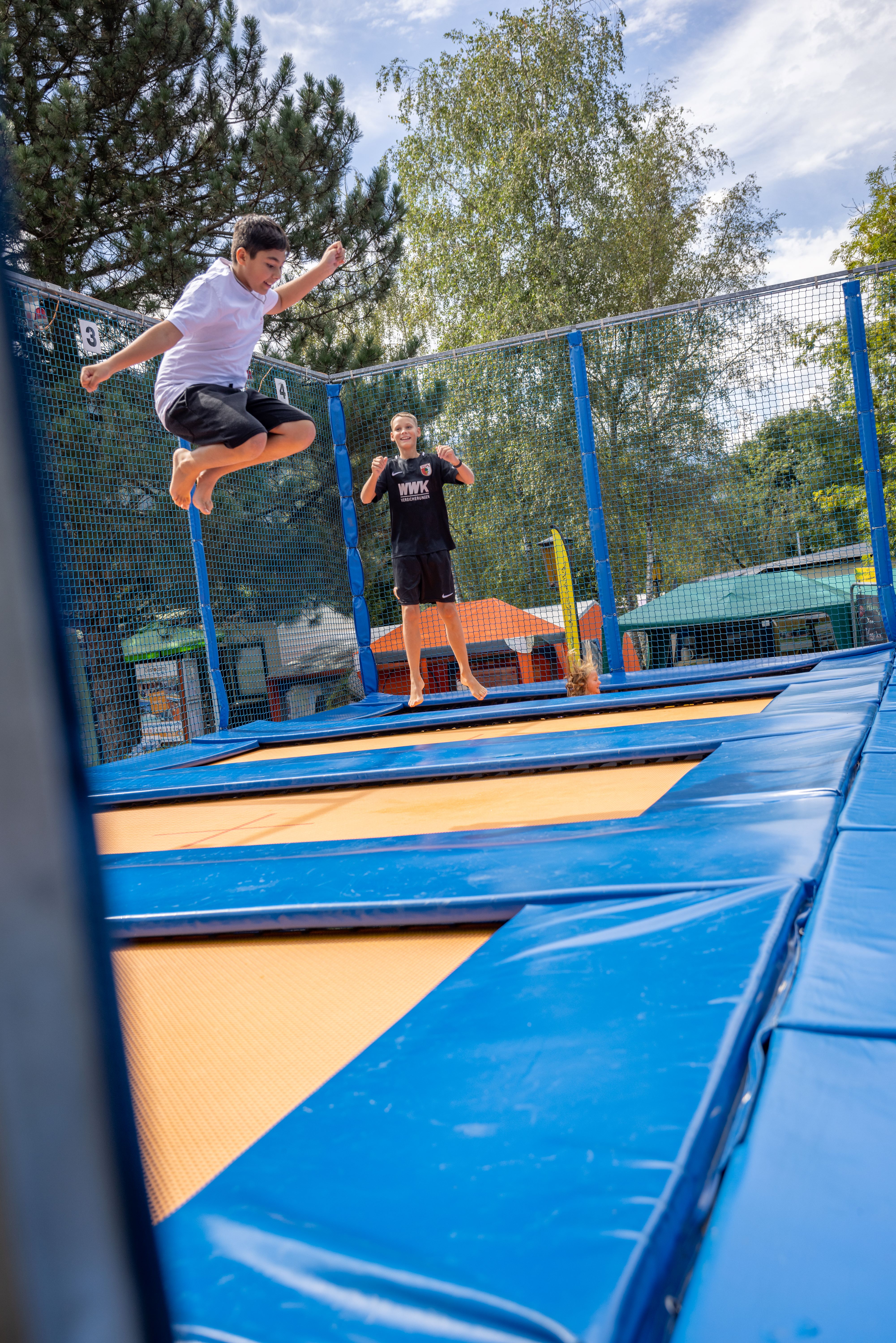 Kinder springen auf Trampolinen im Campingplatz.