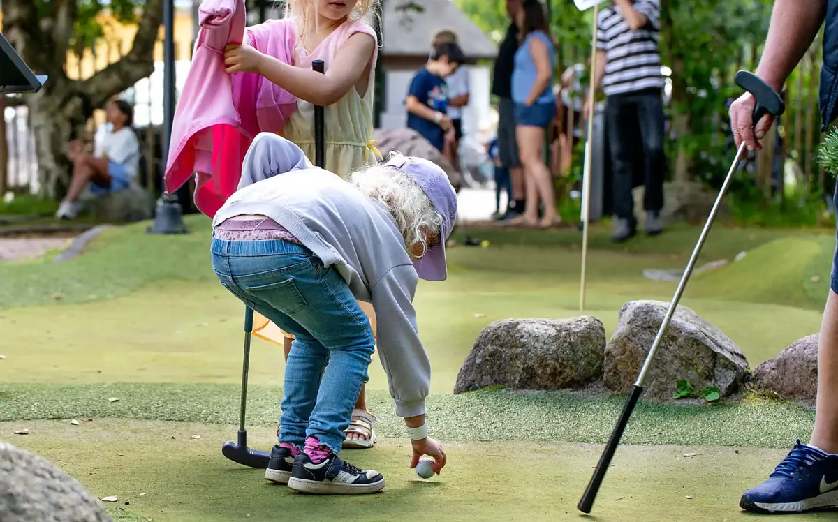 Children playing mini golf at Hvidbjerg Strand Feriepark campsite.