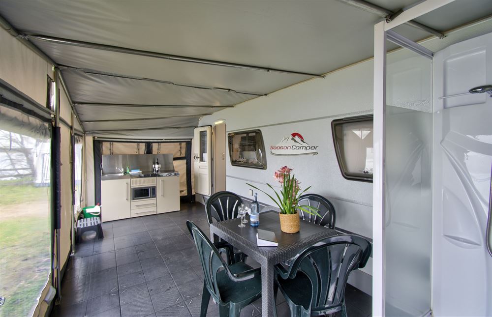 Interior of a camping mobile with a table, chairs, and flowers.