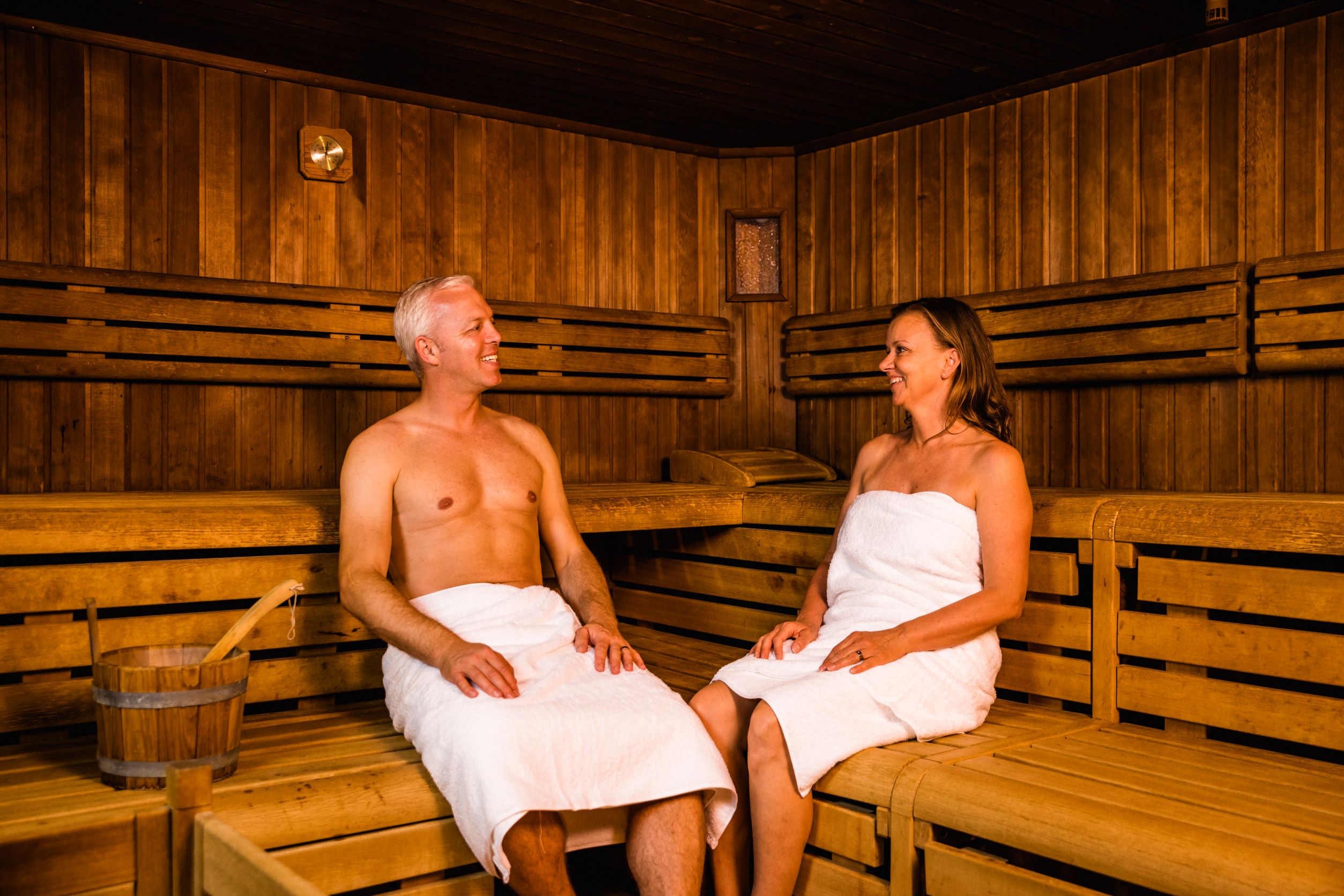 En mand og en kvinde sidder i en træsauna på Camping Wirthshof
