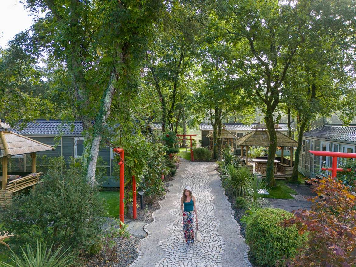 Una donna che cammina su un sentiero di ghiaia in un campeggio con capanne e alberi