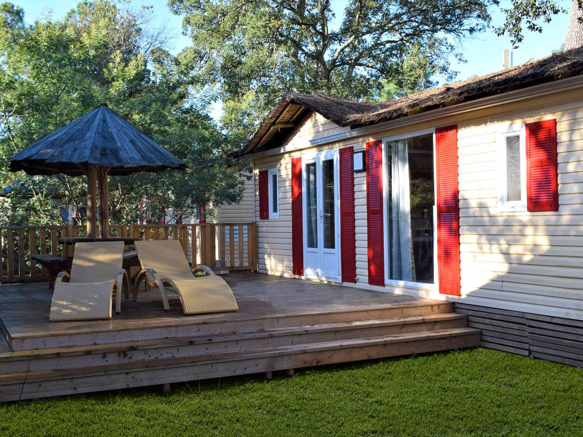 Una casa per camper accogliente con terrazza, sdraio e un ombrellone