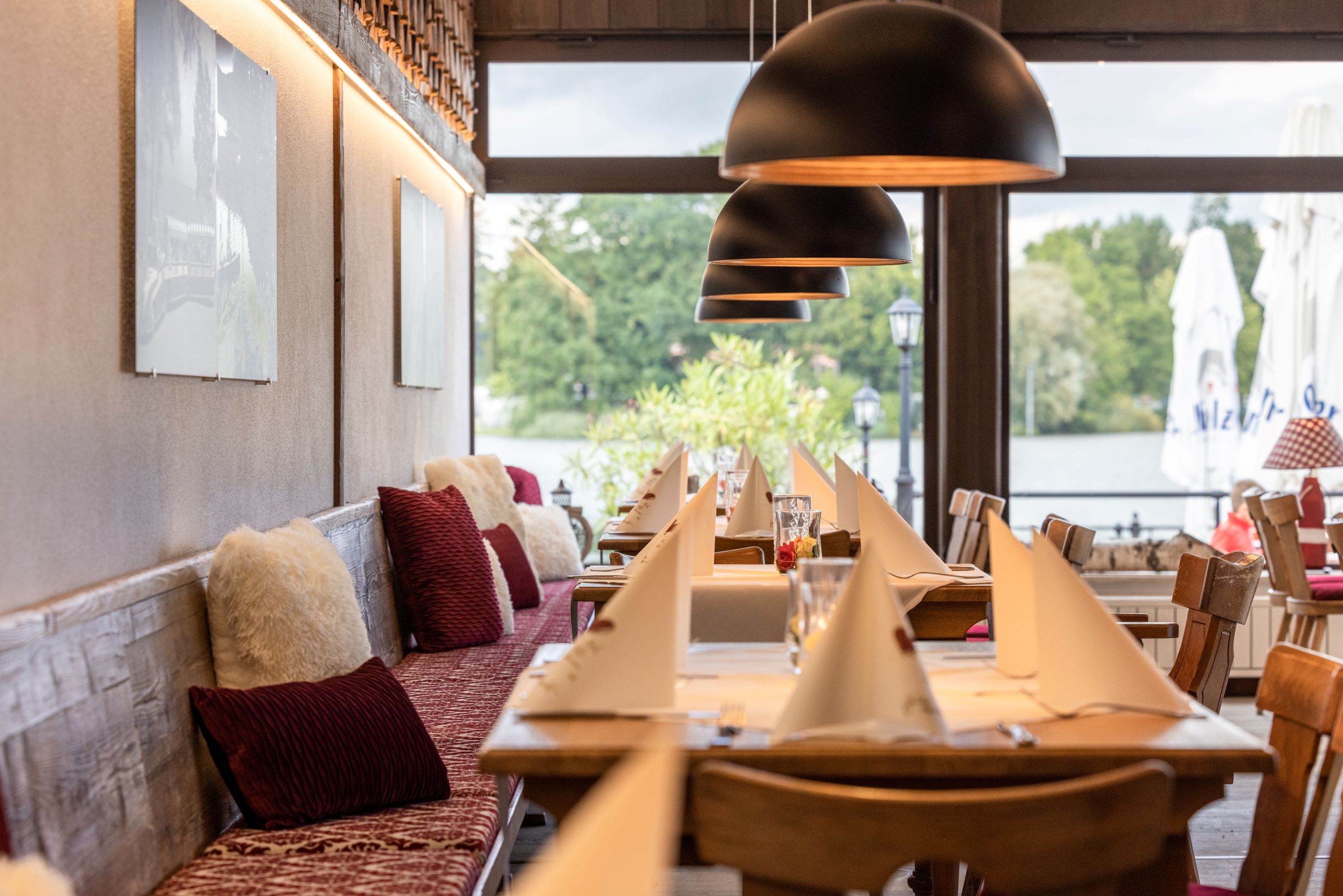 Innenansicht des Restaurants Strandcamping Waging am See mit Sitzgelegenheiten und Tischen.